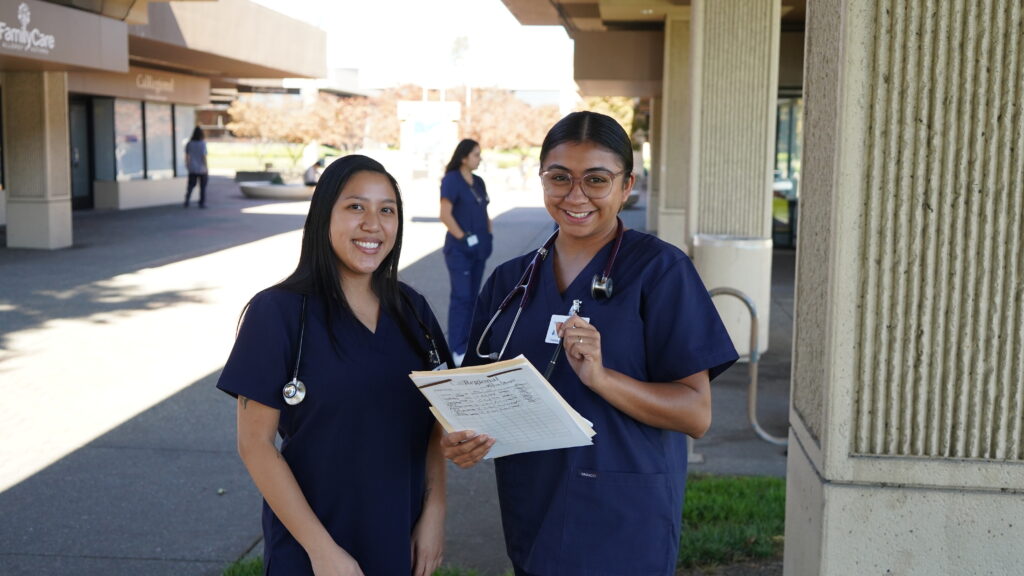 Aspiring Registered Nurses smile outside of their classroom.