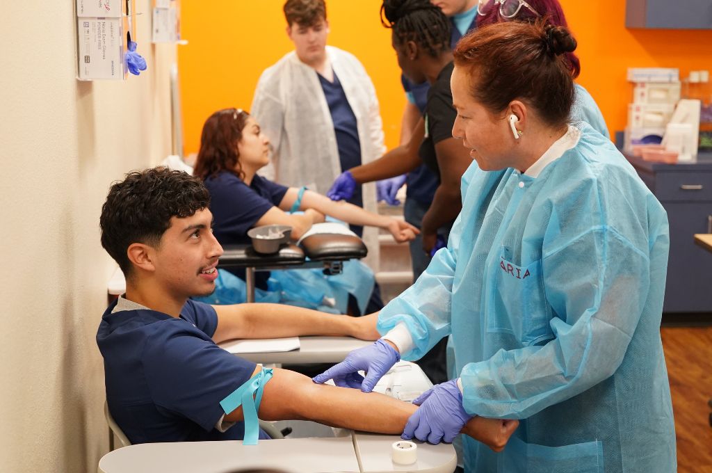 Students practice blood draws during phlebotomy training.