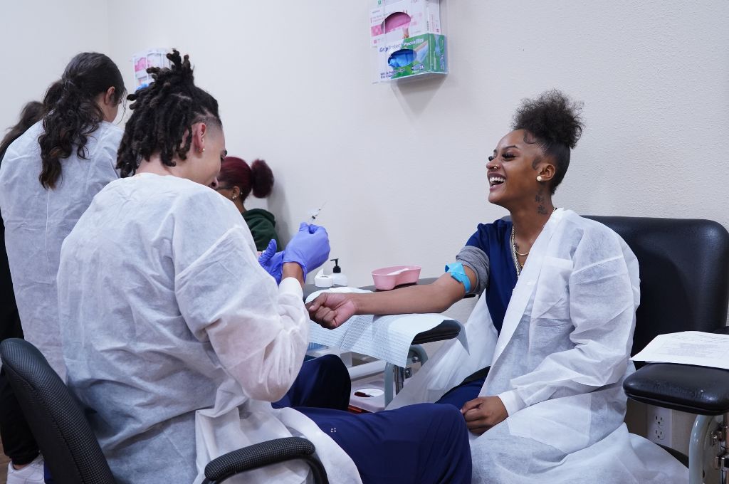 Students practice blood draws during phlebotomist training.