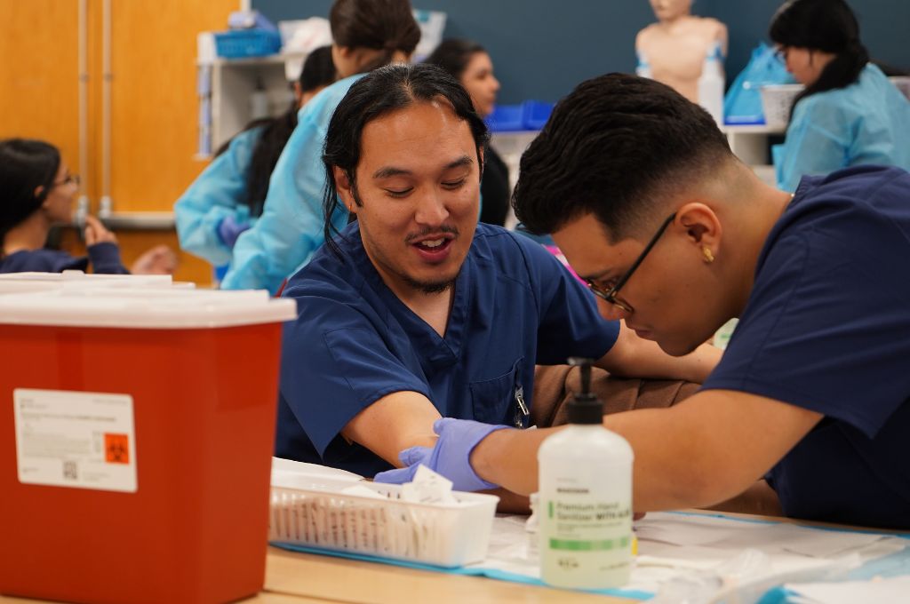 Instructor guiding medical assistant students through clinical lab training at an Antioch campus